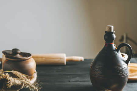 Black wooden table with rolling pin, burlap, spikelets, clay pot and oil bottle in sunlight. Copy spaceの写真素材