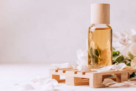 Cosmetic, aroma or massage oil on wooden podium in form of pallet on light plaster surface with...