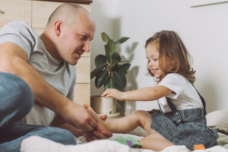 Father plays with little daughter 2-4 on floor. Dad tickles kids feet. Family, having funの写真素材