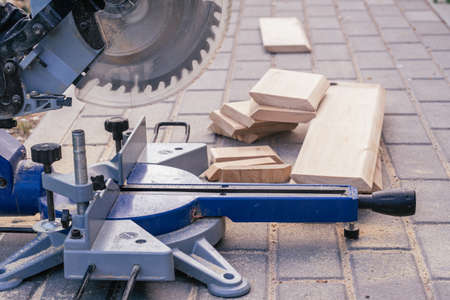 Professional miter saw on paving slabs with trim planks for house cladding. Construction and repair...