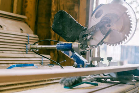 Professional miter saw standing on stack of boards with trim planks for house cladding. Construction and repair conceptの写真素材