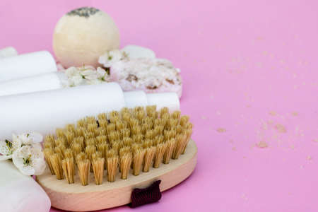 White cosmetic bottles, bath bomb, handmade soap, bath salt, massage brush, sponge, cotton buds with cherry flowers on a pink background. Natural organic cosmetics concept.の写真素材