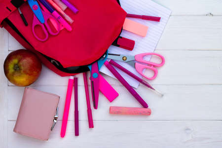 Pink school supplies, backpack on a white wooden background. Top view. Copy space. Education and back to school concept.の写真素材