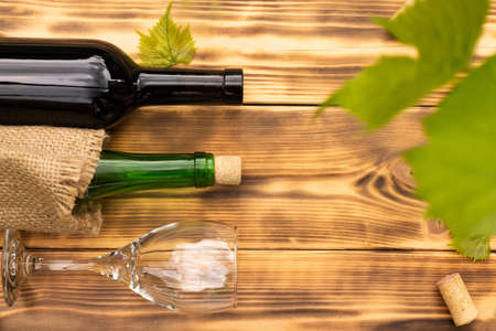 Wine glass, corkscrew, corks, wine bottles, grapevine on rustic burnt wooden background. Top view, copy spaceの写真素材