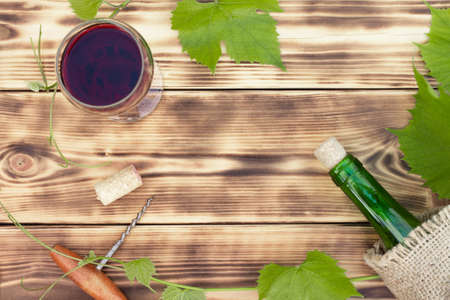 Wine glass, corkscrew, corks, wine bottles, grapevine on rustic burnt wooden background. Top view, copy spaceの写真素材