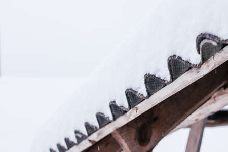 Fragment of roof made of old corrugated slate covered with white snowの写真素材