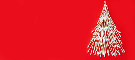 Wooden cotton swabs, laid out in shape of Christmas tree on red background. Banner. Flat lay. Copy...