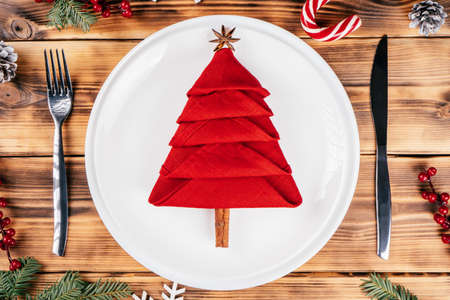 Step-by-step tutorial: Fold linen napkin in shape of Christmas tree. New Year table setting. Step 10: Add anise star and cinnamon stick for top and trunk. Top viewの写真素材