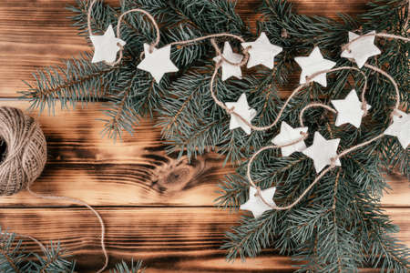 Christmas stars homemade cold porcelain garland with spruce branches on background of burnt wood. Top viewの写真素材