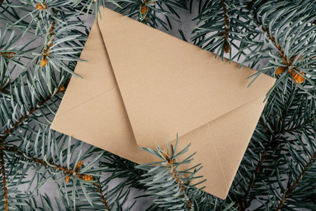 Background creative image with close up texture of fir branches with beige kraft paper envelope. Merry christmas and happy new year. Top view. Copy spaceの写真素材