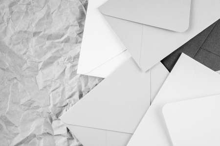 Monochrome background image of black and white cardboard envelopes lying randomly on crumpled paper background. Top view. Copy spaceの写真素材