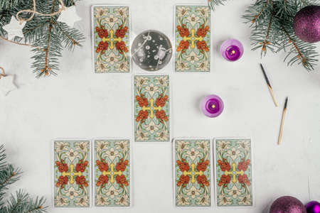 Tarot cards spread on white concrete surface with Christmas tree branches, candles and decorations. Minsk, Belarus, 11/19/2021のeditorial素材