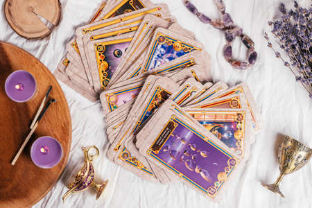Tarot cards spread face up on white cloth sheet with wooden tray, lavender, candles and attributes. Top view. Minsk, Belarus, 09/27/2021のeditorial素材