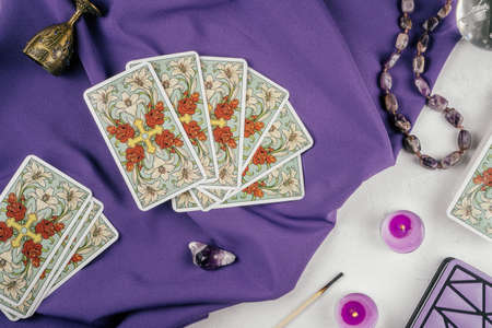 Tarot cards fanned back up on purple cloth on white concrete surface with candles and attributes. Top view. Minsk, Belarus, 11/19/2021のeditorial素材