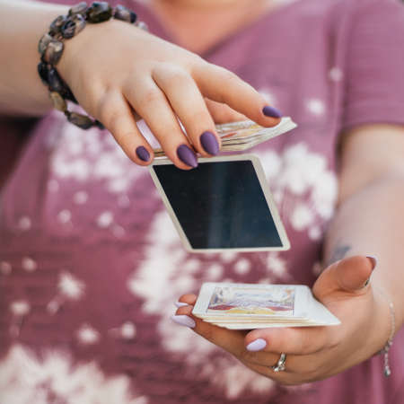 Female hands with bracelet and purple nails throw deck of tarot cards in air. Minsk, Belarus,...