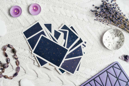 Tarot cards spread face down on white knitted surface with crystal ball, lavender, candles and accessories. Top view. Minsk, Belarus, 11.10.2021の写真素材