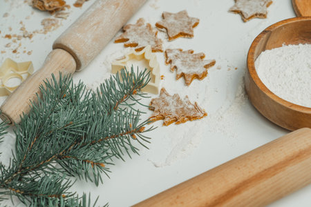 Partially blurred raw gingerbread cookies in shape of christmas trees and stars lie on kitchen countertop next to spruce branch, flour and rolling pin. Christmas pastries. Merry Christmas, New Yearの写真素材