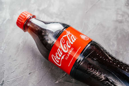 Clear plastic bottle of Coca-Cola lie on gray concrete surface. Bottle with red label inscribed with unique refreshing taste in Russian. Minsk, Belarus - 12.11.2021のeditorial素材