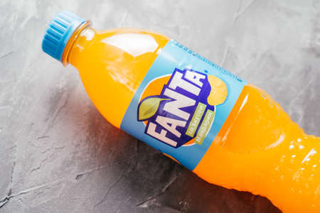 Transparent plastic bottle of Fanta lie on gray concrete surface. Bottle with orange drink and blue label inscribed with tangerine taste in Russian. Minsk, Belarus - 12.11.2021のeditorial素材