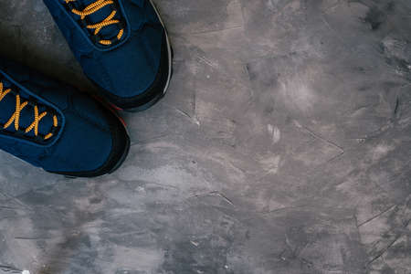 Blue warm winter or autumn sneakers with orange shoe laces on dark gray concrete surface. Top view. Copy space. Flat layの写真素材
