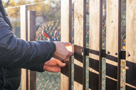 Hand of carpenter attaching wooden plank to metal construction for checking and reconstructing...
