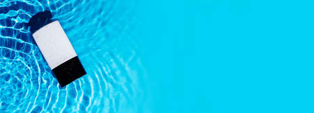 Banner fashion trendy bottle of perfume toilet water on blue water wave splash background. Advertising of beauty cosmetology product. Black and white container. Copy space. Elegant luxury scentの写真素材