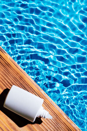 Wood desk with white bottle of nose drops, allergy aerosol for sinusitis cure. Control breath. Blue transparent reflect water surface ocean. Hot warm dry air summer beach. Vertical. Place for text.の写真素材