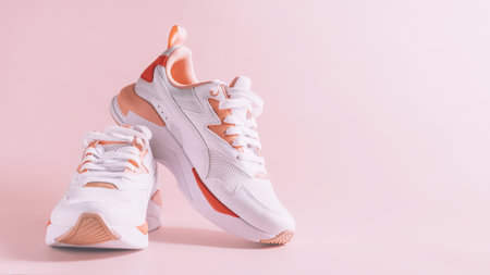 White womens sneakers with coral inserts on pink background