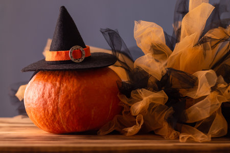 Halloween orange pumpkin in a witch hat on a blue background with black and orange tulle, copy space.の写真素材