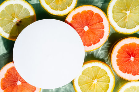 White circle copy space in transparent fresh exhilarant wave water with flecks background, lemon, grapefruit citrus slices. Summer freshness, eating healthy beach travel drinks concept. flat layの写真素材