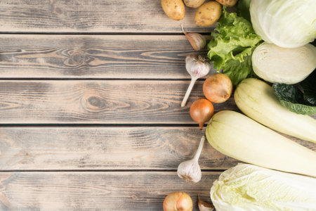Vertical row of fresh farm vegetables on wooden table, top view. Seasonal foodstuffs sorting. Nitrate free food or healthy diet concept. Objects layout. Planking. Cooking ingredients. Place for text.の写真素材
