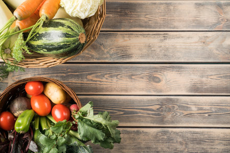 Two wicker baskets with different fresh farm vegetables on gray wooden table, top view. Bowls full of ripe harvest. Food or healthy diet concept. Planking. Place for text. Nitrate free nutrition.の写真素材
