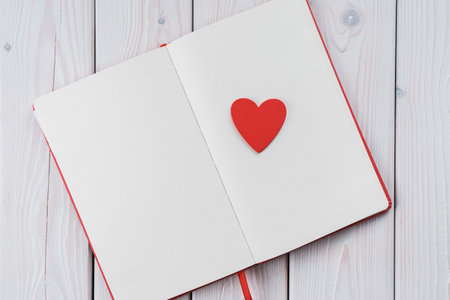 Red diary notebook with white papers, craft red paper heart on page. Love letter message for beloved people, confession and feelings for saint Valentines Day or woman day. Copy space, top viewの写真素材