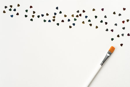 Paintbrush draw and mark small colorful paper hearts on white background. Decorative foil and paper...