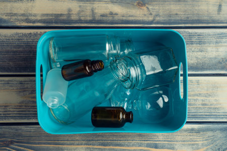 Blue plastic square box full of transparent plastic and glass bottles on wooden background. development, recycling and sort. Nondegradable rubbish and environmental crisis. top viewの写真素材