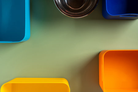 Multicolored plastic and metal triangle containers on green background. Storage takeaway, garbage....