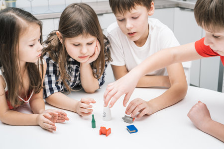 Top view of group of children playing board card game geistes blitz on white table in kitchen,...
