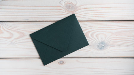 Flat lay of closed sealed green emerald envelope on grey wooden table. Correspondence, mailing, post office, stationary, invitation, document, greeting card. Studio, top view, copy space, mock up.の写真素材