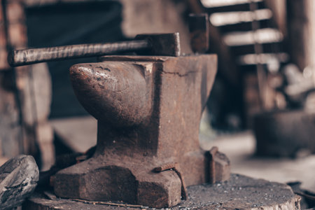 Process metal with hammer on anvil in forge. Strike iron outdoors in workshop. Metalworking,...