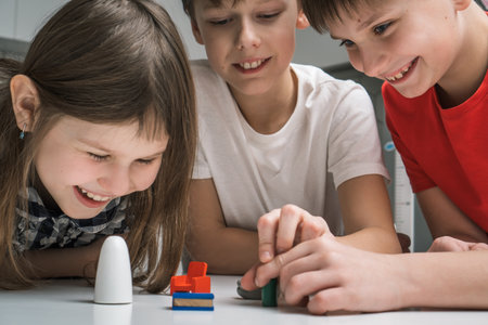 Joyful little school kids play toy mini furniture on table closeup. Portrait of children holding...