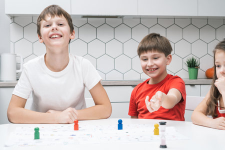 Smiling, blissful children playing board game with pieces and dice with time limit. Family fun games. Educational strategy and logic playing together. Strategic board game with dice and figuresの写真素材