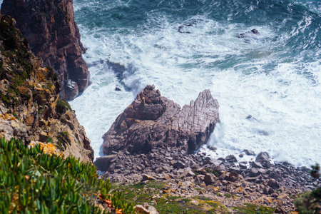 Top view of rocky beach seashore coastline surrounded by foamy waves, steep mountains cliffs covered with green grass on windy day. Summer, holiday, travelling, seascape, landscape, nature, storm.の写真素材