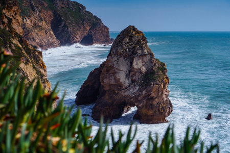 Picturesque view of steep rock in blue near beach seashore coastline surrounded by water sea mountains cliffs covered with green grass. Summer, holiday, travelling, seascape, tourism, ocean.の写真素材