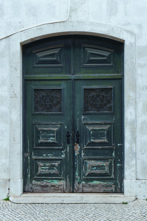 Ornate old ancient green wooden door of stone building house decorated with forgings carvings ornaments with peeling paint. Architecture, historical buildings, vintage, retro, decoration. Vertical.の写真素材