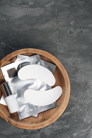 Top view .Beauty and health. Natural eco-friendly materials in cosmetology. Patches, strips under eyes, white bottle lie in wooden bowl standing on gray countertop. Make-up artist's MOCKUP.の写真素材