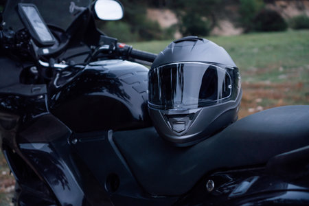Motorcycle tourism. Close - up of black new motorcycle with helmet on seat is in nature .Tourism travel. Adventures vacations. Motorcycle gear. Motorcycle races .Hobbies and hobbieds.の写真素材