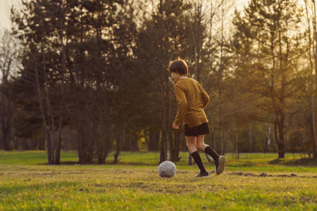 Football practice. Summer sports camp. 11-13 a teenager in sports uniform in early summer morning trains on field against background of forest . Sports and health. Children's sports sections.の写真素材