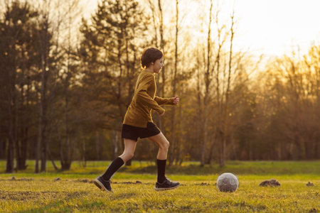 Summer sports camp. 11-13 teenager in sports uniform trains on field in early summer morning against background of forest. Sports and health. Hobbies and hobbies. Football practice.の写真素材