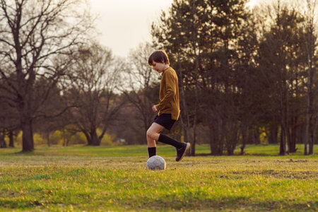 Sports training. Teenage boy of 11-13 years old in sports uniform trains on field with soccer ball in summer morning . Sports and health. Children's sports sections. Hobbies and hobbies.の写真素材
