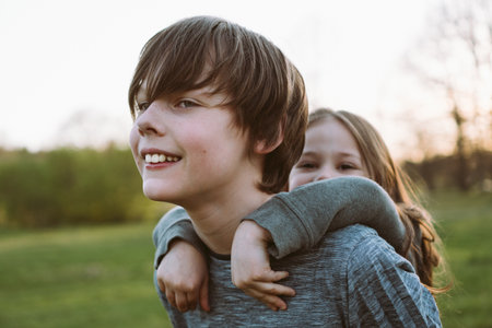 Happy family portrait. Brother holds his younger sister behind his back, they have fun and laugh on...